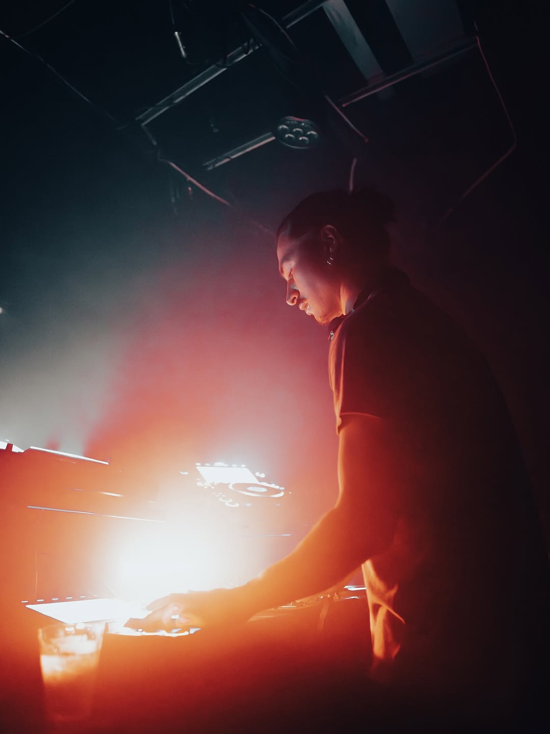 光の中でミキサーを操作するDJ