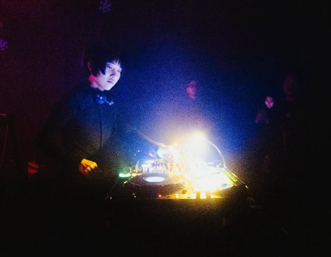 青と黄色の光の中でミキサーを操作するDJ