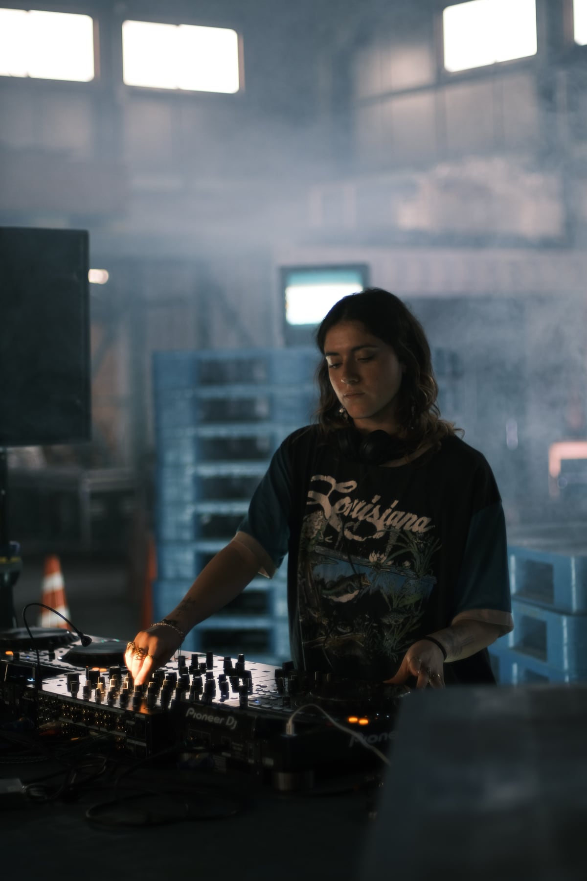 光が差し込む会場で機材を操作するDJ