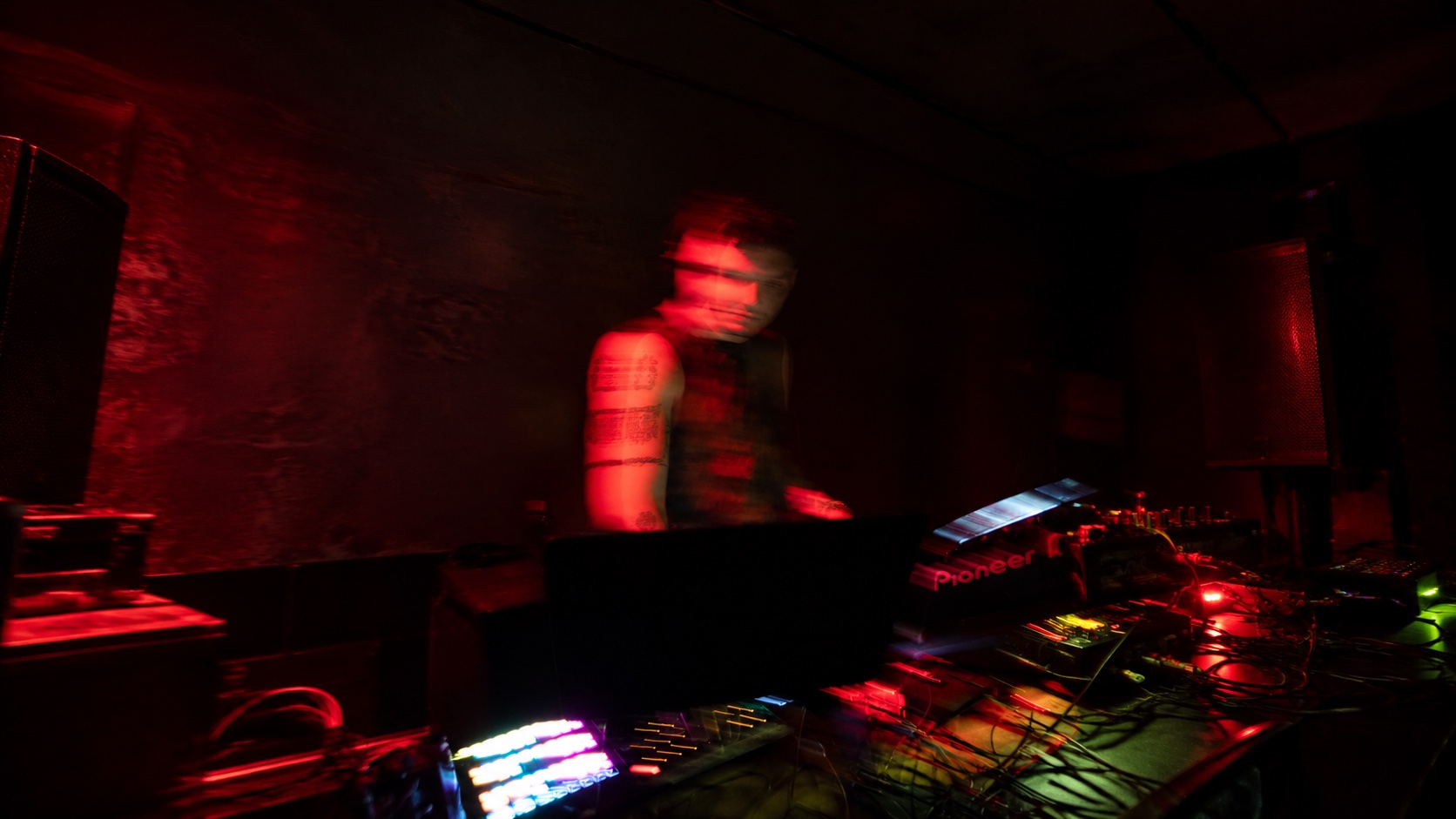 赤い照明の中で演奏するDJ